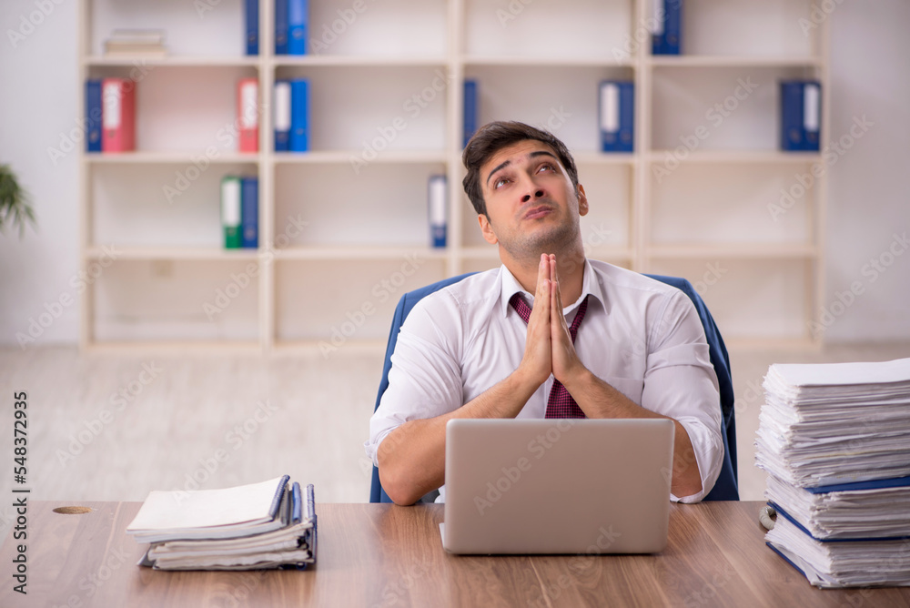 Young male employee and too much work in the office Young male employee and too much work in the office