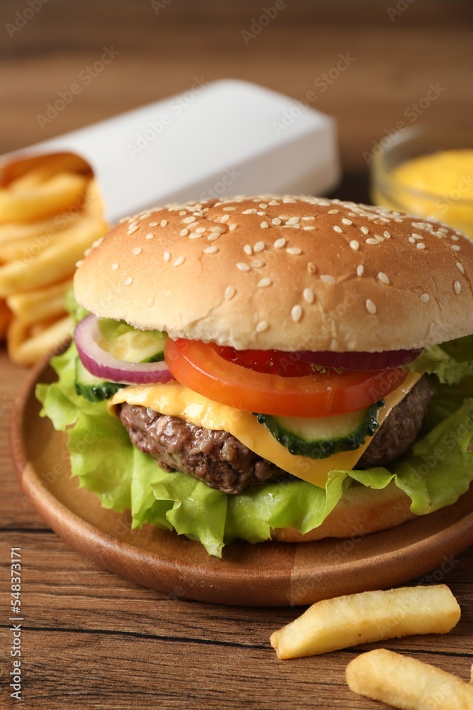 Delicious burger, sauce and french fries served on wooden table, closeup Delicious burger, sauce and french fries served on wooden table, closeup