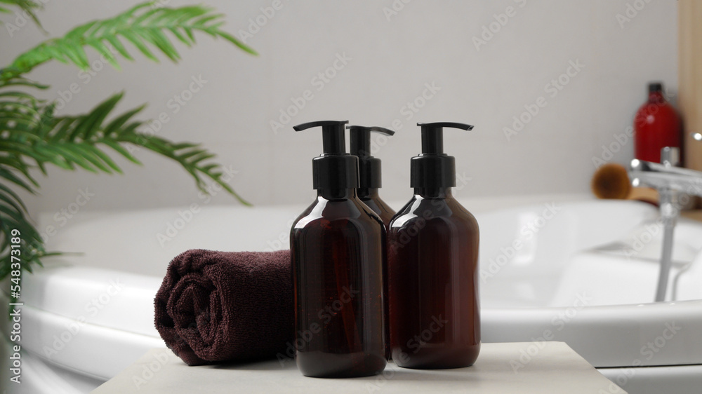 Bath foam and other personal hygiene products in bottles and rolled towel on small table in bathroom Bath foam and other personal hygiene products in bottles and rolled towel on small table in bathroom