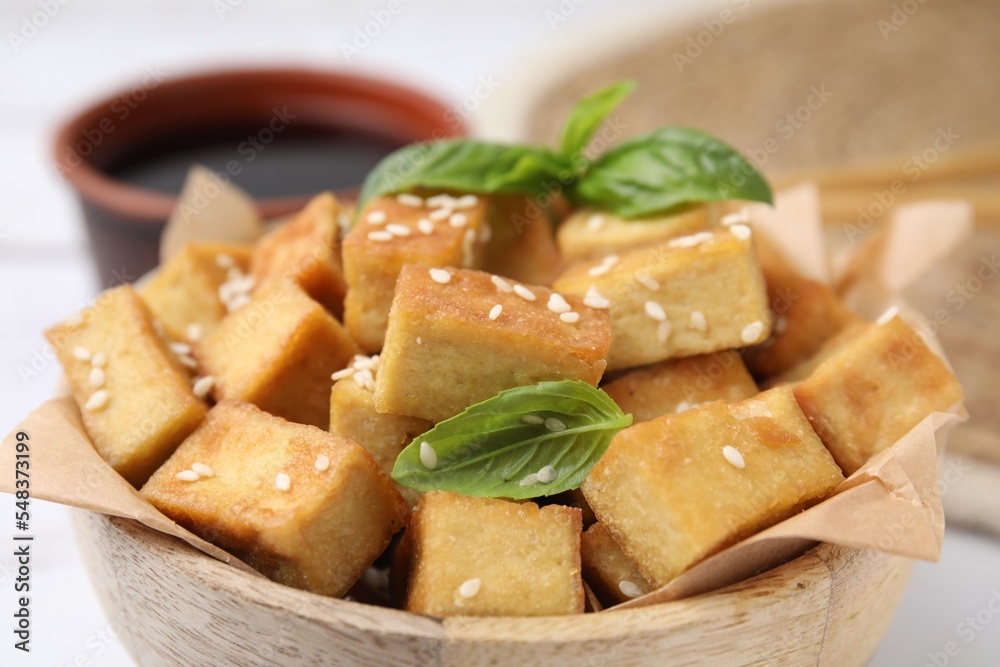 Bowl with delicious fried tofu, basil and sesame seeds, closeup