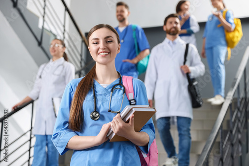 Portrait of medical student with books on staircase in college, space for text