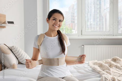 Foto Woman with orthopedic corset sitting in bedroom