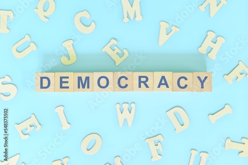 Democracy government form concept. Wooden blocks typography flat lay in blue background.