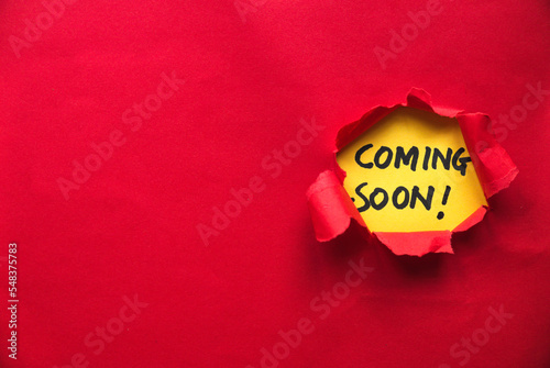 Red torn paper with a yellow paper written with coming soon. Copy space. photo