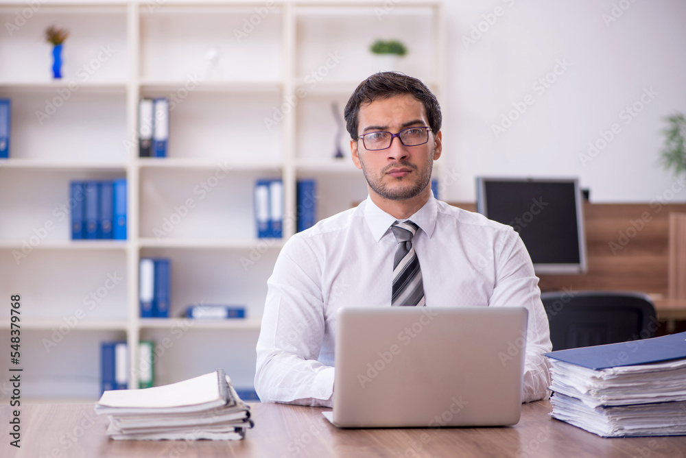 Young male employee unhappy with excessive work at workplace