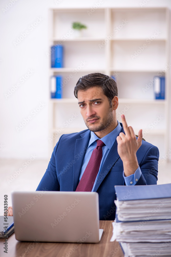 Young male employee and too much work in the office Young male employee and too much work in the office