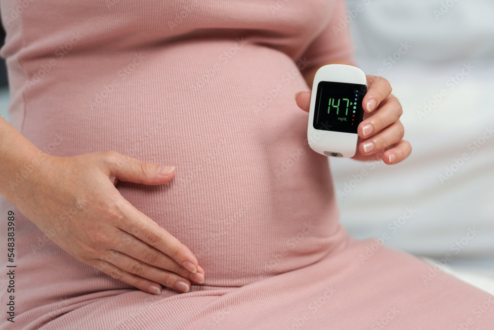 pregnant woman holding glucose meter with result of measurement sugar high level. gestational diabetes concept. pregnant woman holding glucose meter with result of measurement sugar high level. gestational diabetes concept.