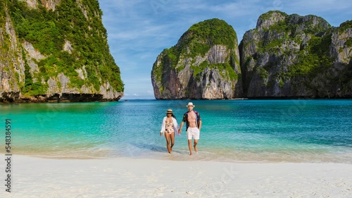 Thai women and caucasian men in swimshort walk on the beach of Maya Bay, beach Koh Phi Phi Thailand in the morning with turqouse colored ocean. photo