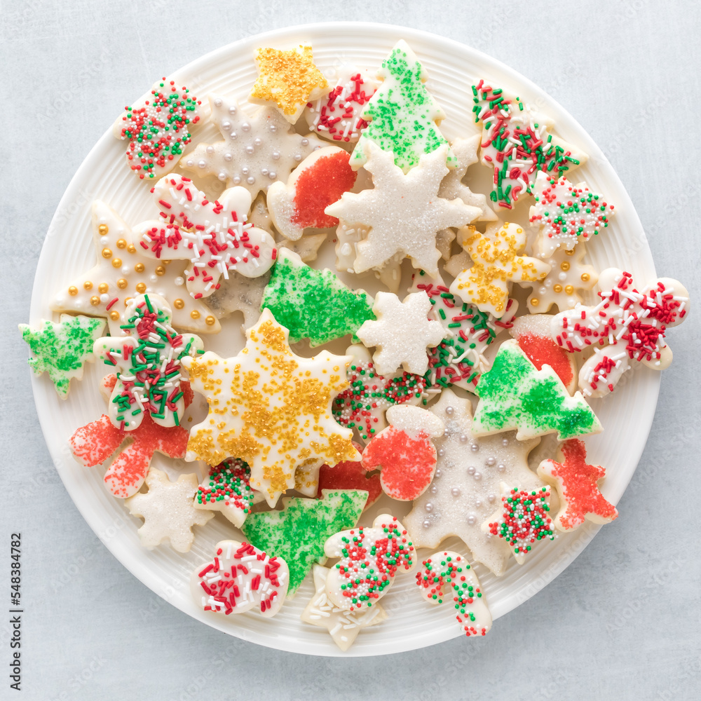 A plate filled with homemade icing sugar cookies of various shapes and sizes. A plate filled with homemade icing sugar cookies of various shapes and sizes.