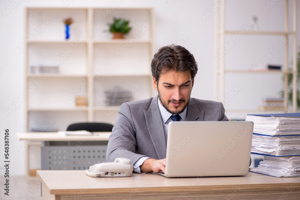 Young male employee and too much work in the office Young male employee and too much work in the office