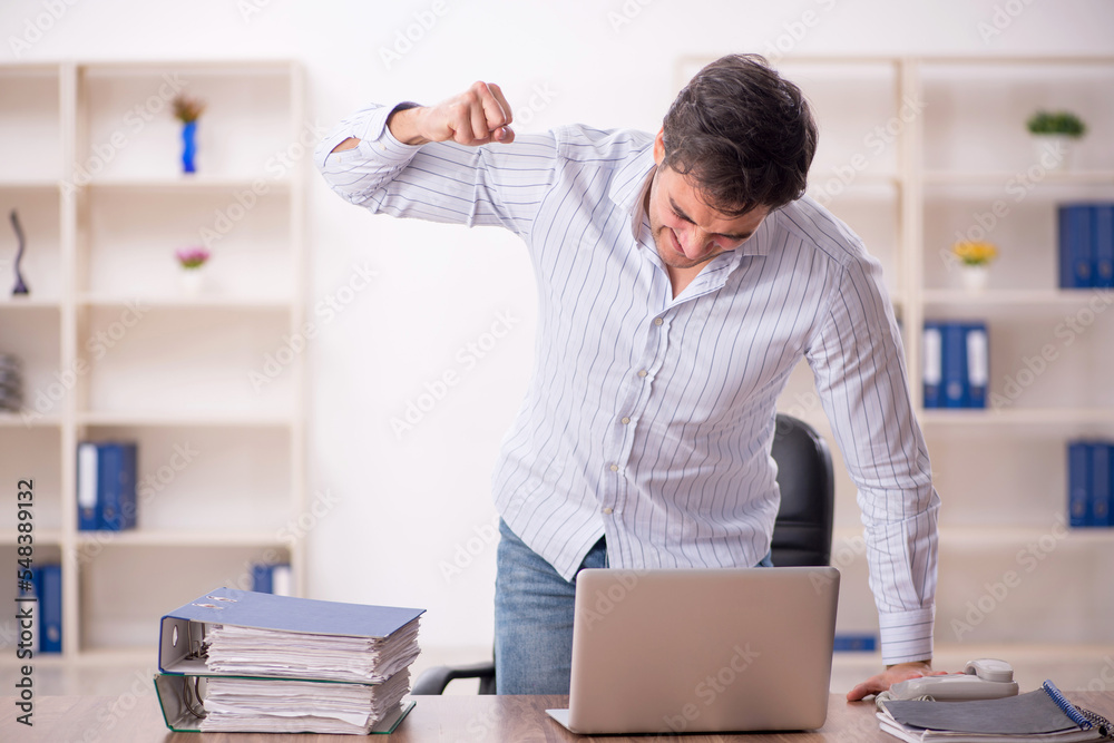 Young male employee and too much work in the office Young male employee and too much work in the office