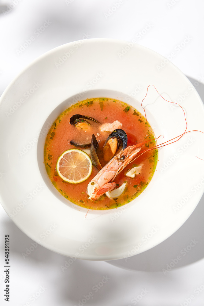 Traditional italian fish soup with shrimp, mussels and salmon. Seafood soup on white background. Tom yam kung with seafood. Spicy fish soup with prawns and lime on light background. Trendy food. Traditional italian fish soup with shrimp, mussels and salmon. Seafood soup on white background. Tom yam kung with seafood. Spicy fish soup with prawns and lime on light background. Trendy food.