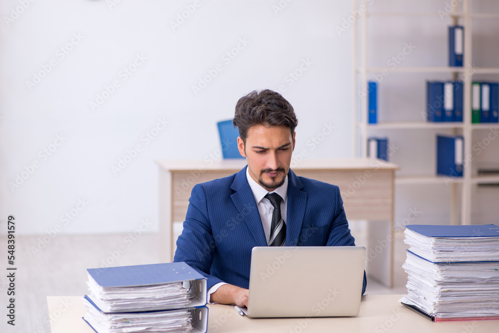 Young male employee and too much work in the office Young male employee and too much work in the office