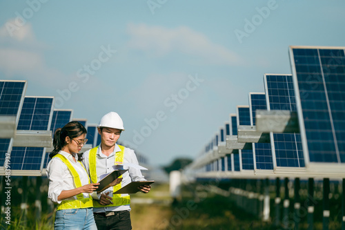 Asian Young Inspector Engineer man and female walking checking operation in solar farm