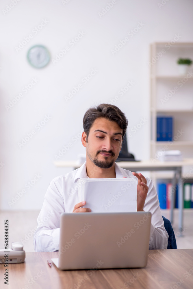 Young male employee and too much work in the office Young male employee and too much work in the office