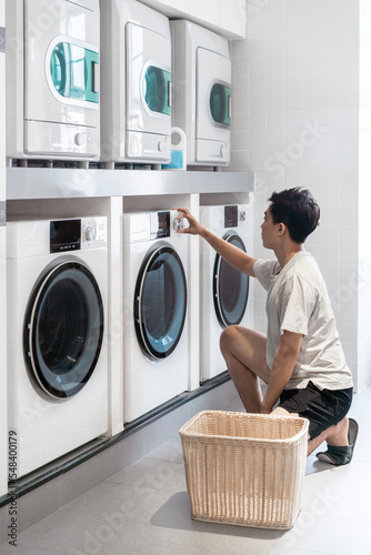 Asian young man is doing laundry in the public laundry room.
