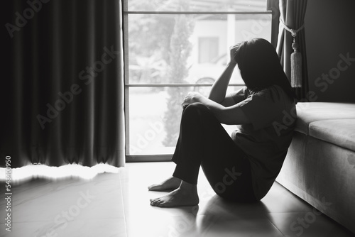 Schizophrenia with lonely and sad in mental health depression concept. Depressed woman sitting against floor at home with dark room feeling miserable. Women are depressed, fearful and unhappy. © doidam10