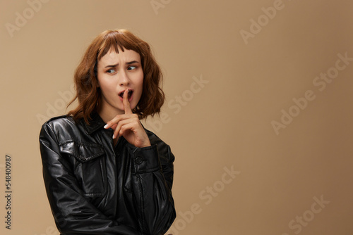 Funny adorable stylish pretty redhead lady in leather jacket sunglasses posing isolated on pastel beige studio background. Copy space Banner Offer. Over black concept. Fashion Cinema. Seasonal Sale