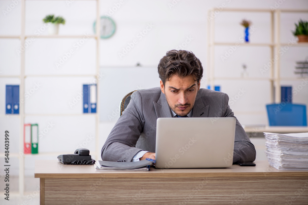 Young male employee sitting at workplace Young male employee sitting at workplace