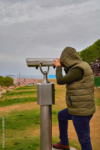  A man on an observation deck looks through a telescope.