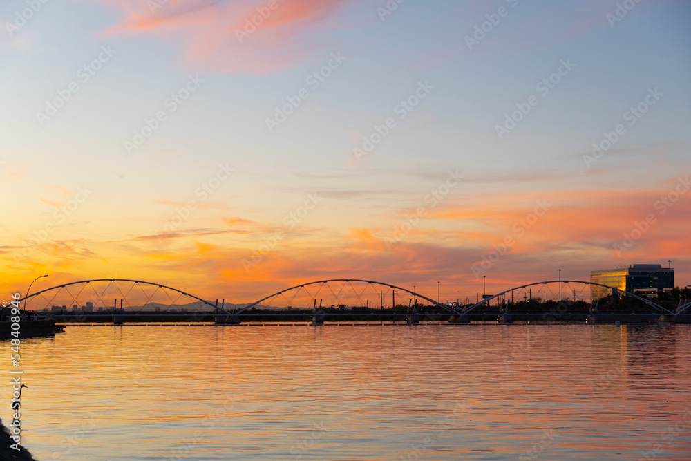 Fototapeta premium Pedestrian bridge over a lake at sunset.