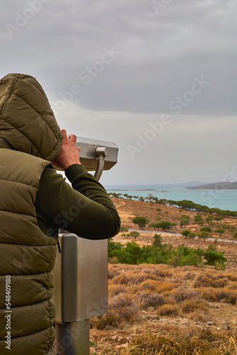  A man on an observation deck looks through a telescope.