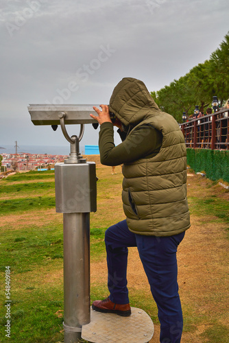  A man on an observation deck looks through a telescope.