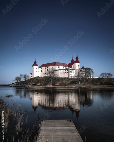 Vertical shot of medieval Lacko Castle reflecting on the still water at night, Sweden photo