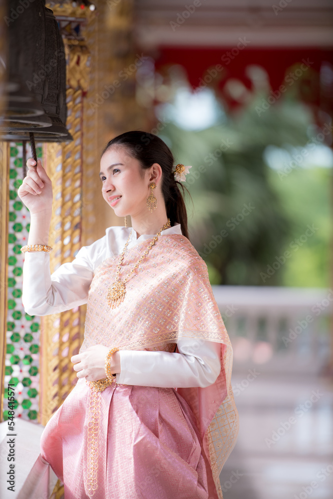 Portrait of a beautiful woman wearing a traditional Thai dress smiling gracefully standing in a temple of Thailand Portrait of a beautiful woman wearing a traditional Thai dress smiling gracefully standing in a temple of Thailand