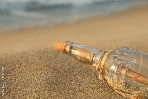 SOS message in glass bottle on sand, closeup