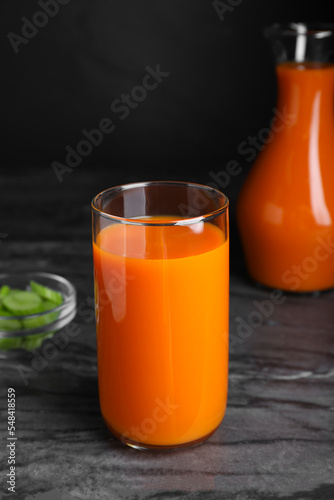 Tasty refreshing carrot juice on black marble table