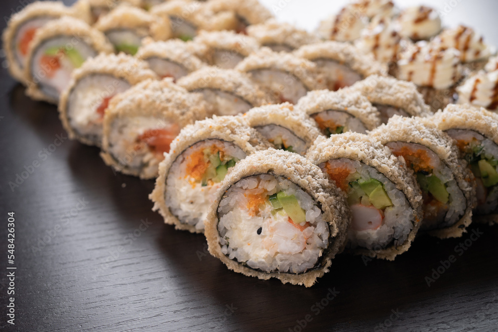 Tempura maki roll on black background. Hot sushi set with salmon, crab and cucumber inside. Modern japanese menu Tempura maki roll on black background. Hot sushi set with salmon, crab and cucumber inside. Modern japanese menu