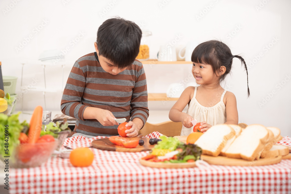 Happy children prepares and eats vegetable salad in kitchen. The concept of healthy diet and lifestyle. Vegan food and healthy lifestyle.Selective Focus. Happy children prepares and eats vegetable salad in kitchen. The concept of healthy diet and lifestyle. Vegan food and healthy lifestyle.Selective Focus.