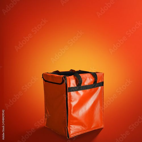 Side view of Red Delivery box backpack on yellow-orange gradient background