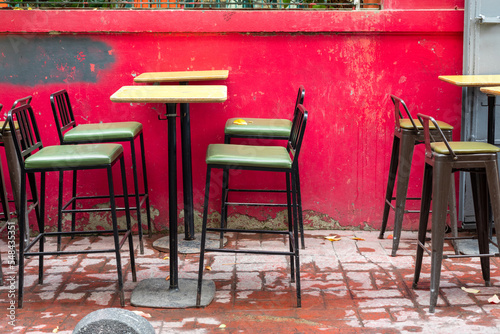 High chairs in the outdoor bar. Chairs in front of a red wall.