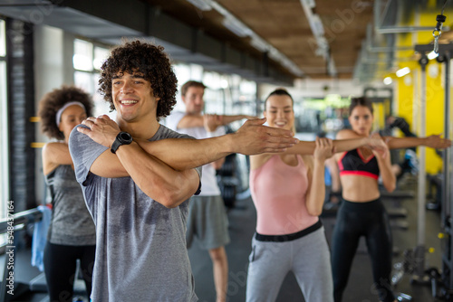 Group of young people, friends smiling and enjoy sport in gym. People exercise, work out concept.