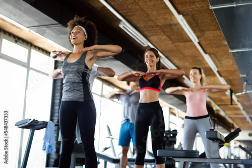 Group of fit people working out in a gym. Multiracial friends exercising together in fitness club.