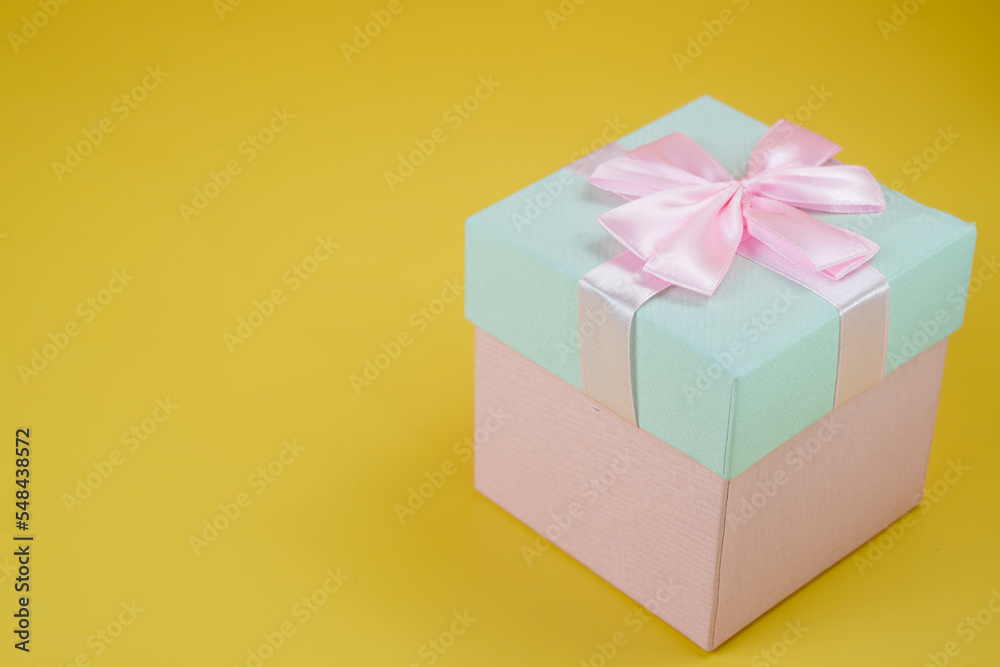 Pink and cyan gift box with ribbon bow isolated on yellow background Pink and cyan gift box with ribbon bow isolated on yellow background