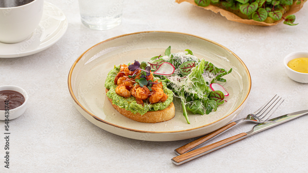 Portion of avocado toast with grilled shrimp and salad Portion of avocado toast with grilled shrimp and salad