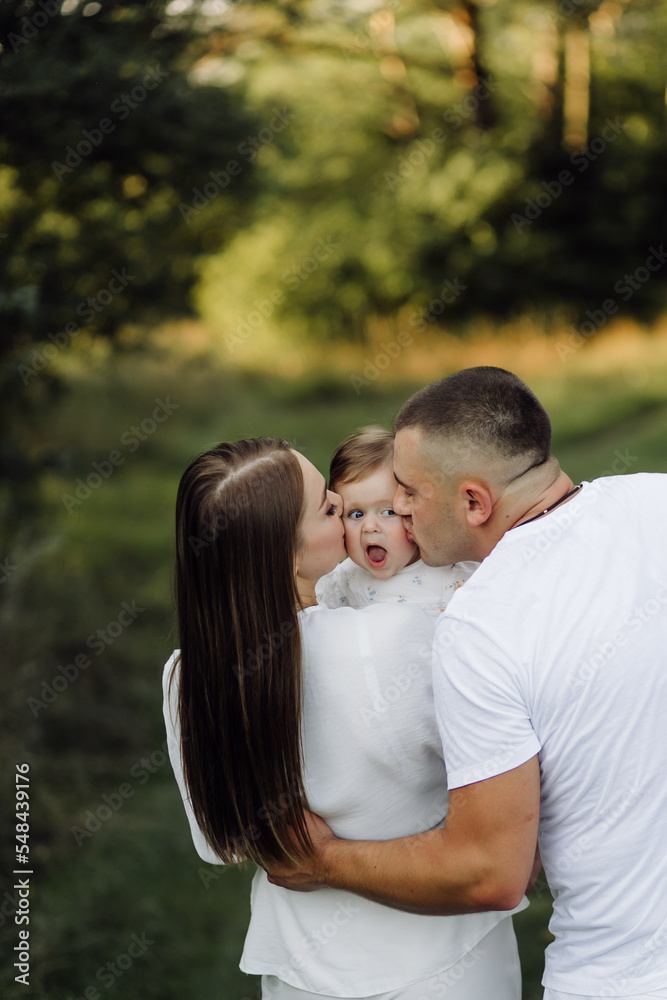 Young family with cute little daughter walking in forest on the sunset Young family with cute little daughter walking in forest on the sunset
