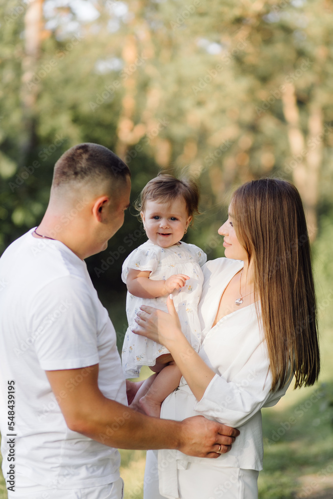 Young family with cute little daughter walking in forest on the sunset Young family with cute little daughter walking in forest on the sunset