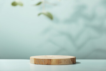Wood slice podium with eucalyptus leaves on blue background for cosmetic product mockup