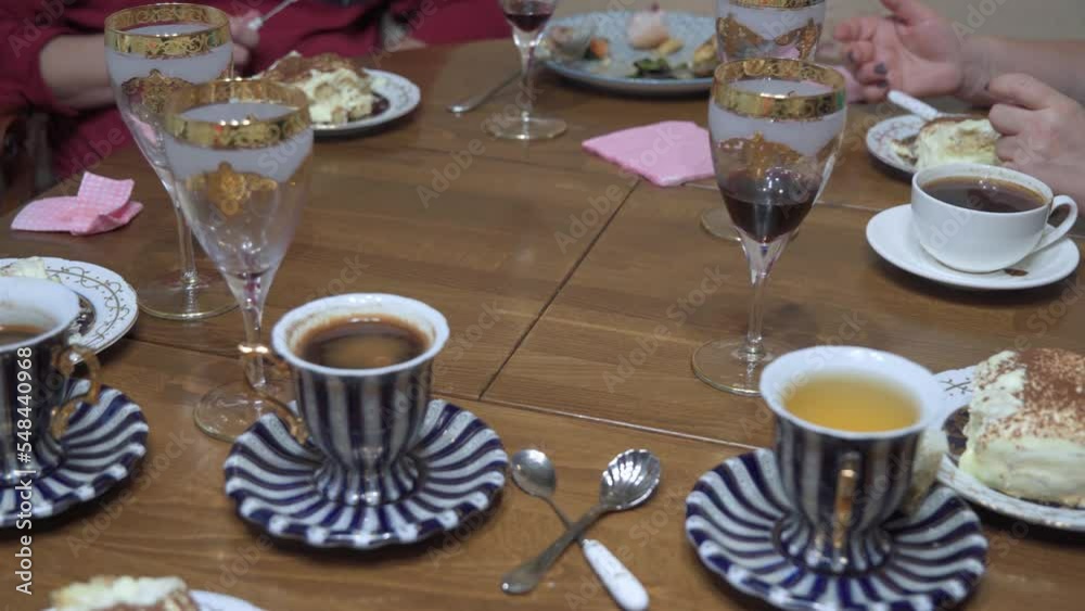 Family dinner. On the table are cups of coffee and tea, various sweets. Hands of people who eat. Family dinner. On the table are cups of coffee and tea, various sweets. Hands of people who eat.