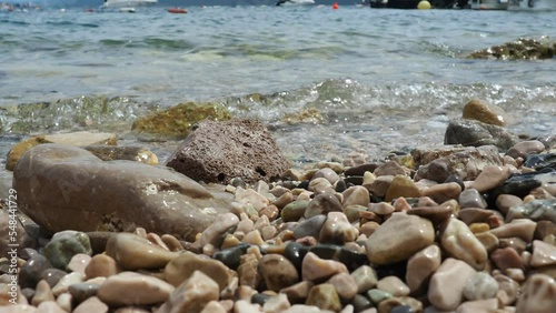 Adriatic Sea, Montenegro Mediterranean. Calm waves of salt water splash against the rocky shore of the plage. Clear water and multi-colored rounded pebbles. Travel business. Sunny beach vacation. photo