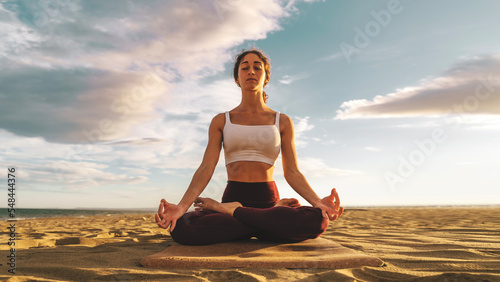 Young woman practicing yoga  doing Ardha Padmasana exercise  meditating in Lotus pose with mudra gesture on the beach