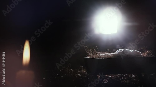 Bright light from the window illuminates the baby Jesus in the manger, Christmas and Christmas background, candle and candles celebrating the birth of Jesus Christ
