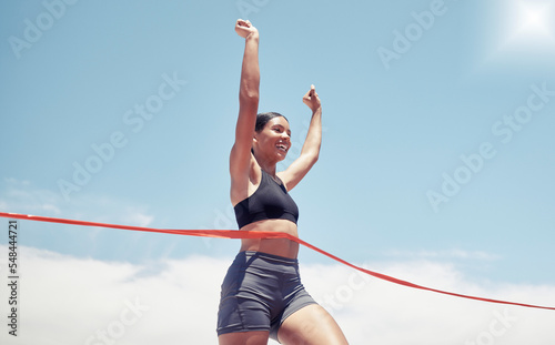 Fitness, winner and sports woman running a race and winning first place in summer in track competition. Runner, goals and happy girl athlete with hands up smile in celebration of a marathon success