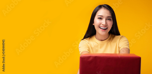 Smiling young asian woman holding red gift box and get happy when get gift box Standing over yellow background Beautiful Asia girl happy smile hold new year gift box present Using for advertisement © Nutlegal