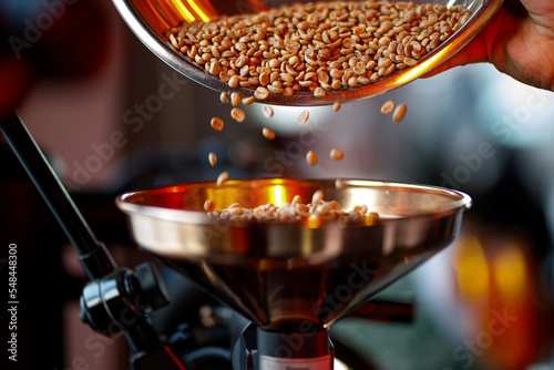 Raw coffee beans are poured into the coffee machine for roasting.