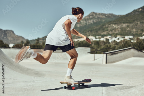 Skating, young man and skateboard at skate park in urban city, fitness or training for trendy hobby. Youth, skater and physical activity in concrete cityscape, skateboarder and sport exercise outdoor